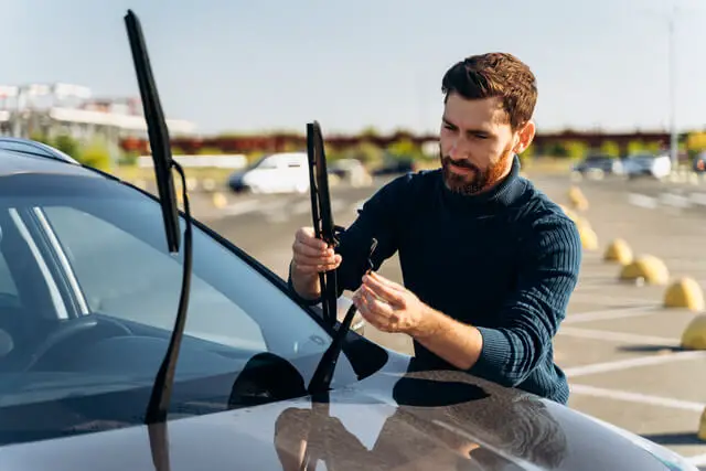 640 man is changing windscreen wipers on a car while standing at the street male replace windshield wipers on car change cars wiper blades concept 1